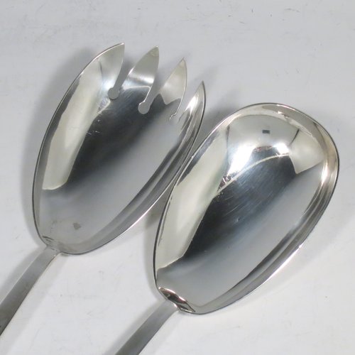An Antique Edwardian Sterling Silver pair of Arts and Crafts salad servers, having very plain bodies with oval bowls, featuring tapered handles with chamfered ends. Made by Elkington & Co., of Birmingham in 1907. The length of these fine hand-made antique silver salad servers are 27 cms (10.75 inches), and the total weight is approx. 132g (4.3 troy ounces).