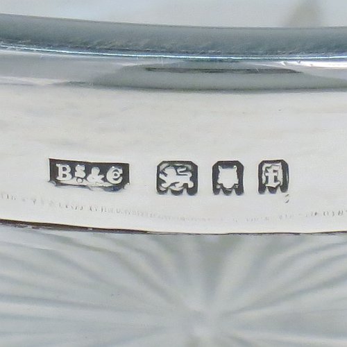 A Sterling Silver and hand-cut crystal salad bowl, having a round body with a plain applied silver rim, sitting on a hand-cut crystal base with floral and leaf engraving, and a star-cut flat base. Made by BS & Co., of London in 1921. The dimensions of this fine hand-made silver and crystal salad bowl are diameter 21 cms (8.25 inches), and height 11 cms (4.25 inches).