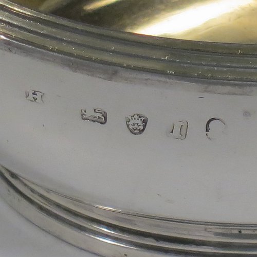 An Antique Georgian Sterling Silver pair of salt cellars, in an oval bath-shaped style, having plain oval bodies, with gold-gilt interiors, applied reeded borders, all sitting on reeded collet feet. Made by either Henry Nutting OR Hannah Northcote of London in 1804. The dimensions of these fine hand-made antique silver salt cellars are length 9.5 cms (3.75 inches), width 6.5 cms (2.5 inches), height 4 cms (1.5 inches), and they weigh a total of approx. 185g (6 troy ounces). Please note that both salt cellars are part-crested.