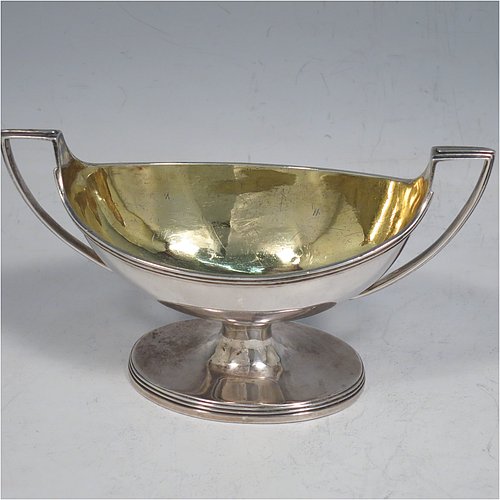 An Antique Georgian Sterling Silver pair of salt cellars, in a boat-shaped style, having plain oval bodies, with gold-gilt interiors, applied reeded borders, and reeded side-handles, all sitting on pedestal feet. Made by either Henry Nutting OR Hannah Northcote of London in 1803. The dimensions of these fine hand-made antique silver salt cellars are length 14 cms (5.5 inches), width 6 cms (2.3 inches), height 7.5 cms (3 inches), and they weigh a total of approx. 217g (7 troy ounces).