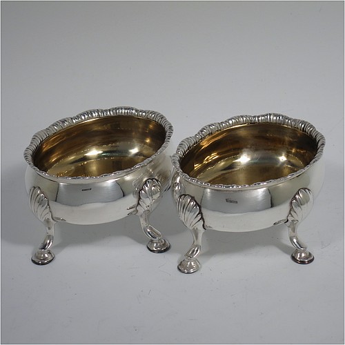 An Antique Georgian Sterling Silver pair of salt cellars, having plain oval bodies, with gold-gilt interiors, applied shaped gadroon borders, and all sitting on four cast hoof feet with shell shoulders. Made by Robert and David Hennell of London in 1767. The dimensions of these fine hand-made antique silver salt cellars are length 9 cms (3.5 inches), width 8 cms (3 inches), height 4.5 cms (1.75 inches), and they weigh a total of approx. 177g (5.7 troy ounces).   