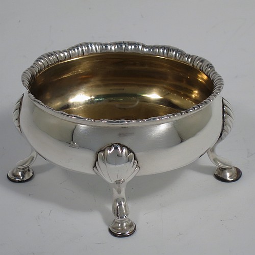 An Antique Georgian Sterling Silver pair of salt cellars, having plain oval bodies, with gold-gilt interiors, applied shaped gadroon borders, and all sitting on four cast hoof feet with shell shoulders. Made by Robert and David Hennell of London in 1767. The dimensions of these fine hand-made antique silver salt cellars are length 9 cms (3.5 inches), width 8 cms (3 inches), height 4.5 cms (1.75 inches), and they weigh a total of approx. 177g (5.7 troy ounces).