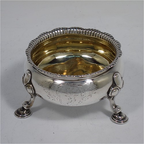 A large and handsome pair of Antique Georgian Sterling Silver salt cellars, having plain round bodies, with gold-gilt interiors, applied shaped gadroon borders, and all sitting on three cast hoof feet with foliate shoulders. Made by Peter Taylor of London in 1750. The dimensions of these fine hand-made antique silver salt cellars are diameter 8 cms (3 inches), height 5 cms (2 inches), and they weigh a total of approx. 224g (7.2 troy ounces). Please note that these items are crested.