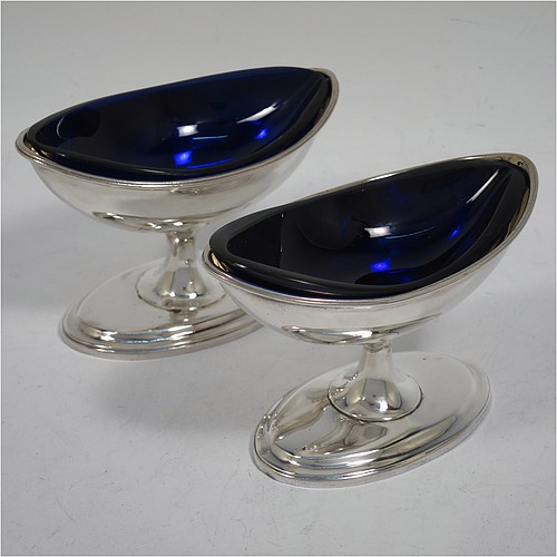 A rare and very handsome Antique Georgian Sterling Silver pair of Irish salt cellars, in a boat-shaped neoclassical style, having plain oval bodies, with gold-gilt interiors and blue-glass liners, with applied reeded borders, all sitting on pedestal feet. Made by John Stoyte of Dublin in 1798. The dimensions of these fine hand-made antique silver Irish salt cellars are length 10 cms (4 inches), width 5.5 cms (2.25 inches), height 6.5 cms (2.5 inches), and they weigh a total of approx. 142g (4.6 troy ounces).   