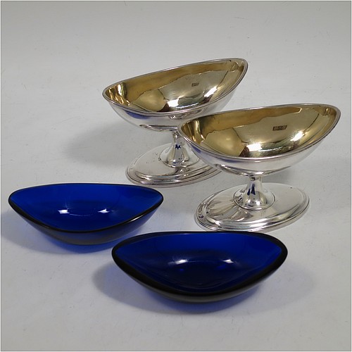 A rare and very handsome Antique Georgian Sterling Silver pair of Irish salt cellars, in a boat-shaped neoclassical style, having plain oval bodies, with gold-gilt interiors and blue-glass liners, with applied reeded borders, all sitting on pedestal feet. Made by John Stoyte of Dublin in 1798. The dimensions of these fine hand-made antique silver Irish salt cellars are length 10 cms (4 inches), width 5.5 cms (2.25 inches), height 6.5 cms (2.5 inches), and they weigh a total of approx. 142g (4.6 troy ounces).
