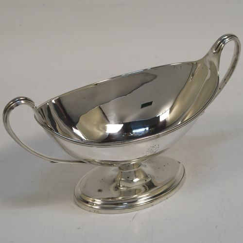 A very handsome Antique Georgian Sterling Silver pair of salt cellars, in a boat-shaped neoclassical style, having plain oval bodies, with blue-glass liners, applied reeded borders, and reeded side-handles, all sitting on pedestal feet. These elegant antique silver salt cellars were made by William Frisbee of London in 1792. The dimensions of these fine hand-made antique silver salt cellars are length 13.5 cms (5.3 inches), width 6 cms (2.3 inches), height 8 cms (3.25 inches), and they weigh a total of approx. 180g (5.8 troy ounces). Please note that both salt cellars have engraved crests.