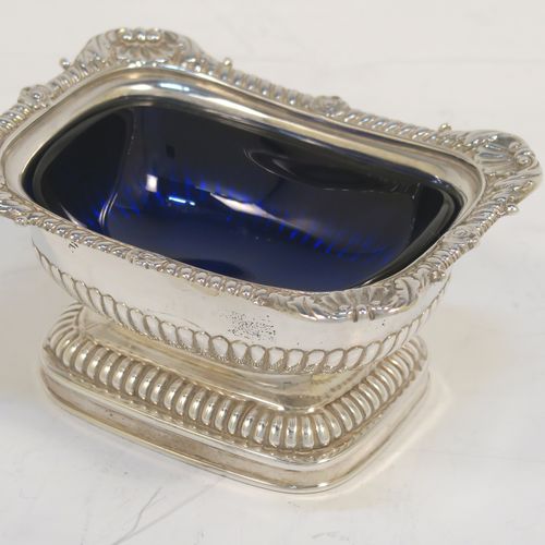 A large and handsome pair of Antique Georgian Sterling Silver salt cellars in a Regency style, having rectangular bodies, with blue-glass liners, applied shell and gadroon borders, half-fluted hand-chased decoration, and all sitting on pedestal bases. These elegant antique silver salt cellars were made in London in 1811. The dimensions of these fine hand-made antique silver salt cellars are length 9.5 cms (3.75 inches), width 7 cms (2.75 inches), height 5 cms (2 inches), and they weigh a total of approx. 237g (7.6 troy ounces). Please note that these items are part crested.