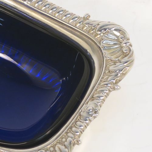 A large and handsome pair of Antique Georgian Sterling Silver salt cellars in a Regency style, having rectangular bodies, with blue-glass liners, applied shell and gadroon borders, half-fluted hand-chased decoration, and all sitting on pedestal bases. These elegant antique silver salt cellars were made in London in 1811. The dimensions of these fine hand-made antique silver salt cellars are length 9.5 cms (3.75 inches), width 7 cms (2.75 inches), height 5 cms (2 inches), and they weigh a total of approx. 237g (7.6 troy ounces). Please note that these items are part crested.