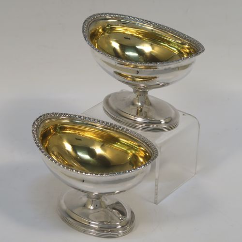 A very handsome Antique Edwardian Sterling Silver pair of salt cellars, in a boat-shaped style, having plain oval bodies, with gold-gilt interiors, applied gadroon borders, and all sitting on oval pedestal feet. These elegant antique silver salt dishes were made by D. and J. Welby of London in 1905. The dimensions of these fine hand-made antique silver salt cellars are length 10 cms (4 inches), width 6.5 cms (2.5 inches), height 6.5 cms (2.5 inches), and they weigh a total of approx. 162g (5.2 troy ounces).