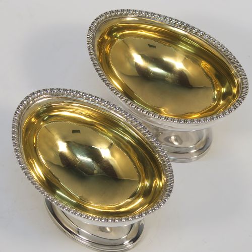 A very handsome Antique Edwardian Sterling Silver pair of salt cellars, in a boat-shaped style, having plain oval bodies, with gold-gilt interiors, applied gadroon borders, and all sitting on oval pedestal feet. These elegant antique silver salt dishes were made by D. and J. Welby of London in 1905. The dimensions of these fine hand-made antique silver salt cellars are length 10 cms (4 inches), width 6.5 cms (2.5 inches), height 6.5 cms (2.5 inches), and they weigh a total of approx. 162g (5.2 troy ounces).