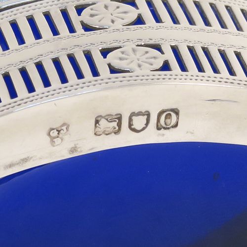 An elegant set of four Antique Edwardian Sterling Silver salt cellars in a Neoclassical style, having oval boat-shaped bodies with hand-pierced galleried sides, internal blue glass liners, and sitting on four fluted flange feet. These beautiful antique silver salt cellars were made by Jackson and Fullerton of London in 1909. The dimensions of this fine hand-made set of four silver salt cellars are length 9 cms (3.5 inches), height 5 cms (2 inches), width 5 cms (2 inches), and they weigh a total of approx. 214g (6.9 troy ounces).