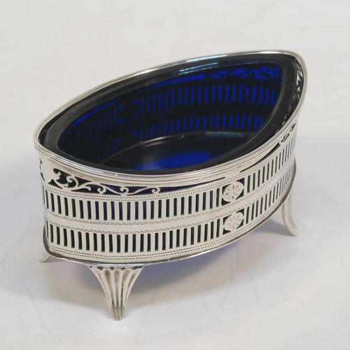 An elegant set of four Antique Edwardian Sterling Silver salt cellars in a Neoclassical style, having oval boat-shaped bodies with hand-pierced galleried sides, internal blue glass liners, and sitting on four fluted flange feet. These beautiful antique silver salt cellars were made by Jackson and Fullerton of London in 1909. The dimensions of this fine hand-made set of four silver salt cellars are length 9 cms (3.5 inches), height 5 cms (2 inches), width 5 cms (2 inches), and they weigh a total of approx. 214g (6.9 troy ounces).