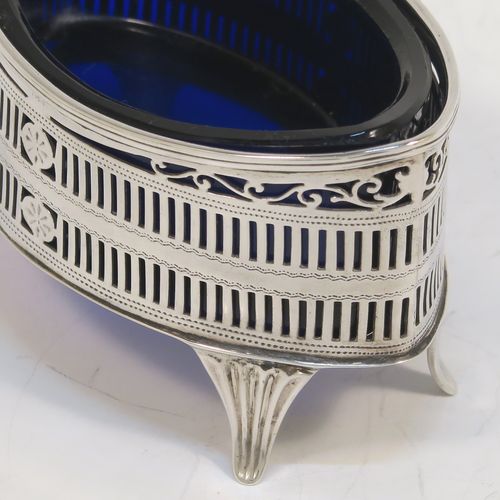 An elegant set of four Antique Edwardian Sterling Silver salt cellars in a Neoclassical style, having oval boat-shaped bodies with hand-pierced galleried sides, internal blue glass liners, and sitting on four fluted flange feet. These beautiful antique silver salt cellars were made by Jackson and Fullerton of London in 1909. The dimensions of this fine hand-made set of four silver salt cellars are length 9 cms (3.5 inches), height 5 cms (2 inches), width 5 cms (2 inches), and they weigh a total of approx. 214g (6.9 troy ounces).