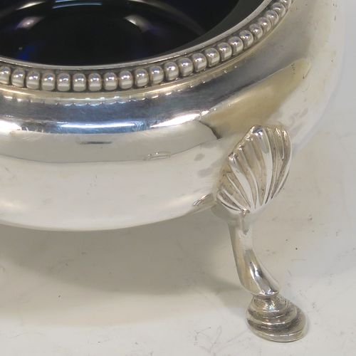 A large and pretty pair of Antique Victorian Sterling Silver cauldron salt cellars, having round bellied bodies with applied bead-edged borders, blue glass liners, and sitting on three cast hoof feet with shell shoulders. These beautiful antique silver salt cellars were made by Arthur Sibley of London in 1862. The dimensions of these fine hand-made antique silver salt cellars are diameter 7 cms (2.75 inches), height 4 cms (1.5 inches), and they weigh a total of approx. 136g (4.4 troy ounces).
