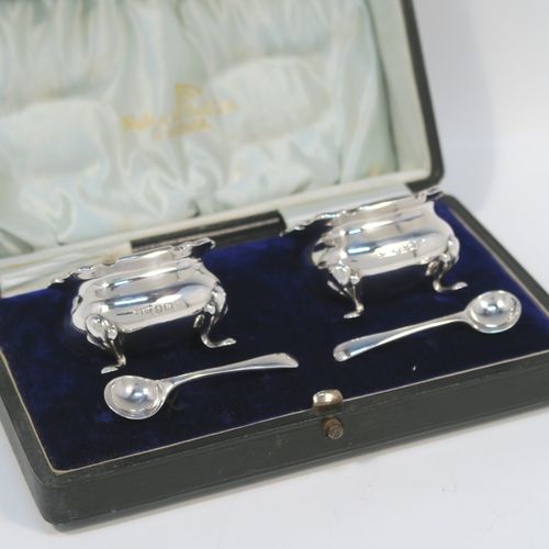 A very pretty pair of Antique Sterling Silver salt cellars, having plain square bellied bodies with with Chippendale style borders, blue glass liners, and sitting on four foliate feet, together with their original salt spoons, and all in their original light blue satin and dark-blue velvet-lined presentation box. This beautiful pair of silver salt cellars and spoons were made by Walker and Hall of Birmingham in 1923. The dimensions of these fine hand-made antique silver salt cellars are 5 cms (2 inches) square, height 8 cms (1.25 inches), and with a total weight of approx. 68g (2.2 troy ounces).   
