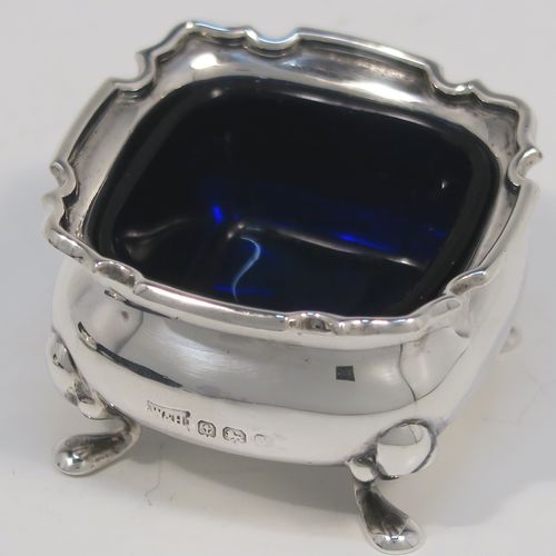 A very pretty pair of Antique Sterling Silver salt cellars, having plain square bellied bodies with with Chippendale style borders, blue glass liners, and sitting on four foliate feet, together with their original salt spoons, and all in their original light blue satin and dark-blue velvet-lined presentation box. This beautiful pair of silver salt cellars and spoons were made by Walker and Hall of Birmingham in 1923. The dimensions of these fine hand-made antique silver salt cellars are 5 cms (2 inches) square, height 8 cms (1.25 inches), and with a total weight of approx. 68g (2.2 troy ounces).