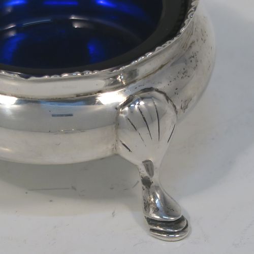 A very handsome pair of Antique Sterling Silver salt cellars, having plain round bellied bodies, with blue-glass liners, applied shaped gadroon borders, and all sitting on three cast hoof feet with reeded shoulders. These elegant silver salt cellars were made by Stokes and Ireland of Chester in 1919. The dimensions of these fine hand-made antique silver salt cellars are diameter 6 cms (2.3 inches), height 3.5 cms (1.3 inches), and they weigh a total of approx. 99g (3.2 troy ounces).