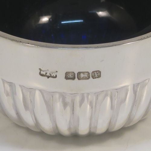 A very pretty set of four Antique Sterling Silver salt cellars, having round bellied bodies with hand-chased half-fluted decoration, with blue glass liners, and sitting on flat bases, together with four original salt spoons, all in their cream satin and green velvet-line presentation box. These beautiful antique silver salt cellars and condiment spoons were made by Mappin and Webb of Sheffield in 1917. The dimensions of these fine hand-made antique silver salt cellars are diameter 5.5 cms (2.2 inches), height 3 cms (1.25 inches), and they weigh a total of approx. 143g (4.6 troy ounces).