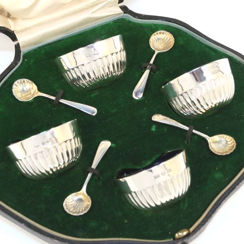 A very pretty set of four Antique Sterling Silver salt cellars, having round bellied bodies with hand-chased half-fluted decoration, with blue glass liners, and sitting on flat bases, together with four original salt spoons, all in their cream satin and green velvet-line presentation box. These beautiful antique silver salt cellars and condiment spoons were made by Mappin and Webb of Sheffield in 1917. The dimensions of these fine hand-made antique silver salt cellars are diameter 5.5 cms (2.2 inches), height 3 cms (1.25 inches), and they weigh a total of approx. 143g (4.6 troy ounces).
