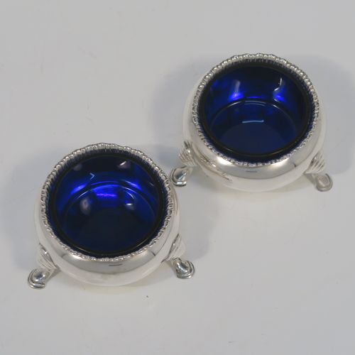 A very handsome pair of Antique Victorian Sterling Silver salt cellars, having plain round bellied bodies, with blue-glass liners, applied shaped gadroon borders, and all sitting on three cast hoof feet with reeded shoulders. These elegant silver salt cellars were made by Francis Boone Thomas of London in 1874. The dimensions of these fine hand-made antique silver salt cellars are diameter 6.5 cms (2.5 inches), height 4 cms (1.5 inches), and they weigh a total of approx. 128g (4 troy ounces).