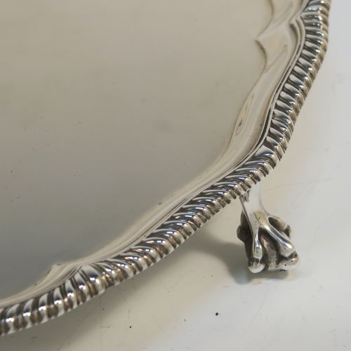 A very elegant Antique Edwardian Sterling Silver salver, having an applied Gadroon border, a plain ground, and sitting on four cast claw and ball feet. This handsome antique silver salver was made by Goldsmiths and Silversmiths of London in 1910. The dimensions of this fine hand-made silver salver are diameter 30.5 cms (12 inches), and it weighs approx. 878g (28 troy ounces).