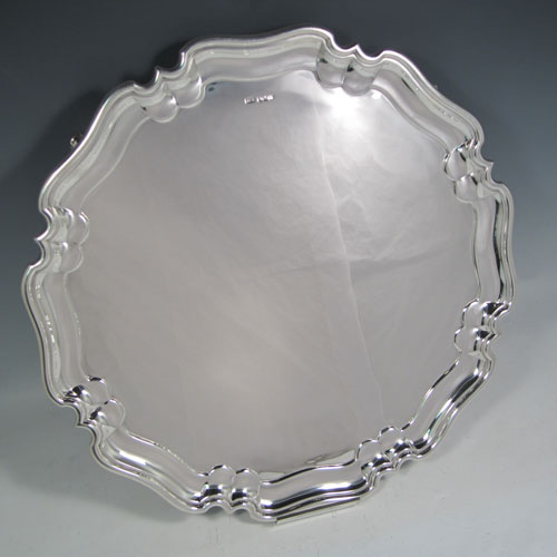 Sterling silver large serving salver, having a round body, with plain burnished ground, a pie-crust style border, and sitting on four scroll feet. Made by Henry Atkins of Sheffield in 1925. The dimensions of this fine hand-made silver salver are diameter 41 cms (16 inches), and it weighs approx. 1,837g (59 troy ounces).
