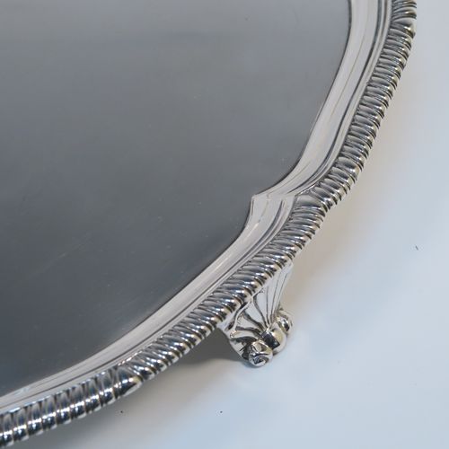 A very elegant Antique Georgian Sterling Silver salver, having an applied shaped gadroon border, a plain ground with a central laurel leaf cartouche., and sitting on three cast scroll and shell feet. This beautiful antique silver salver was made by Hanham and Crouch of London in 1801. The dimensions of this fine hand-made silver salver are diameter 37 cms (14.5 inches), and it weighs approx. 1,288g (41.5 troy ounces).