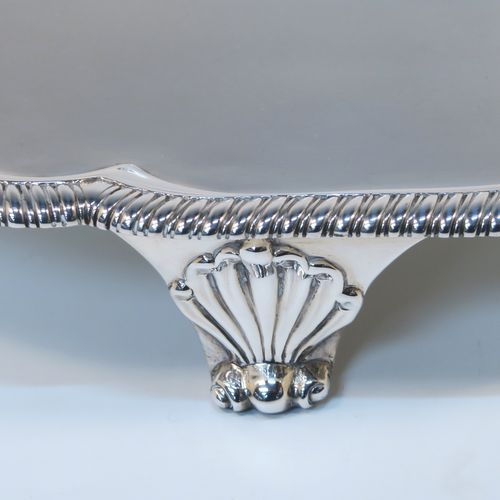 A very elegant Antique Georgian Sterling Silver salver, having an applied shaped gadroon border, a plain ground with a central laurel leaf cartouche., and sitting on three cast scroll and shell feet. This beautiful antique silver salver was made by Hanham and Crouch of London in 1801. The dimensions of this fine hand-made silver salver are diameter 37 cms (14.5 inches), and it weighs approx. 1,288g (41.5 troy ounces).