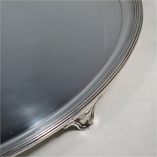 A large Antique Georgian Sterling Silver salver, having an oval body, with a plain burnished ground, an applied Reeded border, and sitting on four cast scroll feet. Made by William Bennett (Possibly) of London in 1801. The dimensions of this fine hand-made silver salver are length 46 cms (18 inches), width 35 cms (13.75 inches), and it weighs approx. 1,735g (56 troy ounces).