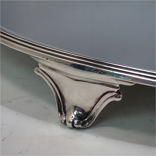 A large Antique Georgian Sterling Silver salver, having an oval body, with a plain burnished ground, an applied Reeded border, and sitting on four cast scroll feet. Made by William Bennett (Possibly) of London in 1801. The dimensions of this fine hand-made silver salver are length 46 cms (18 inches), width 35 cms (13.75 inches), and it weighs approx. 1,735g (56 troy ounces).
