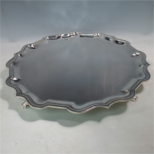 A large Antique Sterling Silver salver, having a round body, with a plain burnished ground, an applied Bath border, and sitting on four cast hoof feet. Made by Carrington and Co., of London in 1915. The dimensions of this fine hand-made antique silver salver are diameter 46 cms (18 inches), and it weighs approx. 2,388g (77 troy ounces).