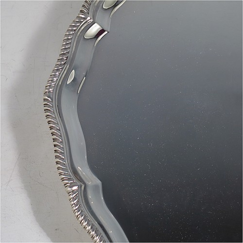 A large Sterling Silver salver, having a round body, with a plain burnished ground, an applied Shaped Gadroon border, and sitting on four cast claw and ball feet. Made by Thomas Bradbury & Sons of Sheffield in 1945. The dimensions of this fine hand-made silver salver are diameter 36 cms (14.25 inches), and it weighs approx. 1,333g (43 troy ounces).
