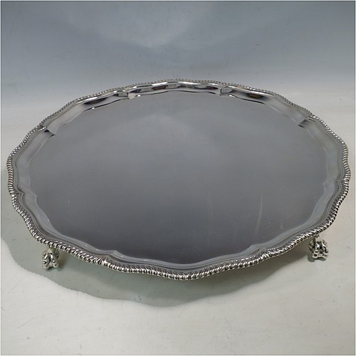 A large Sterling Silver salver, having a round body, with a plain burnished ground, an applied Shaped Gadroon border, and sitting on four cast claw and ball feet. Made by Thomas Bradbury & Sons of Sheffield in 1945. The dimensions of this fine hand-made silver salver are diameter 36 cms (14.25 inches), and it weighs approx. 1,333g (43 troy ounces).