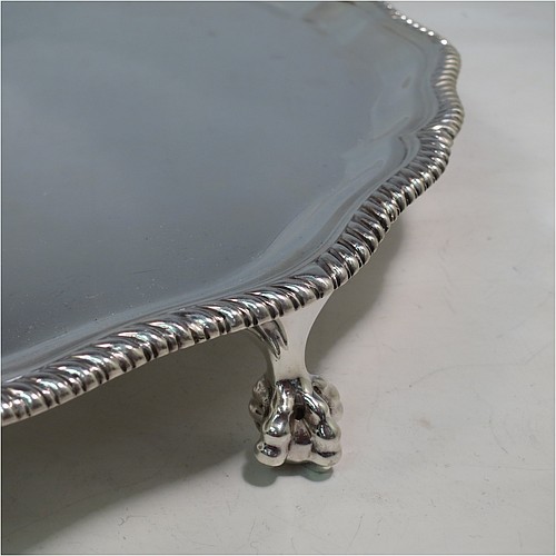 A large Sterling Silver salver, having a round body, with a plain burnished ground, an applied Shaped Gadroon border, and sitting on four cast claw and ball feet. Made by Thomas Bradbury & Sons of Sheffield in 1945. The dimensions of this fine hand-made silver salver are diameter 36 cms (14.25 inches), and it weighs approx. 1,333g (43 troy ounces).