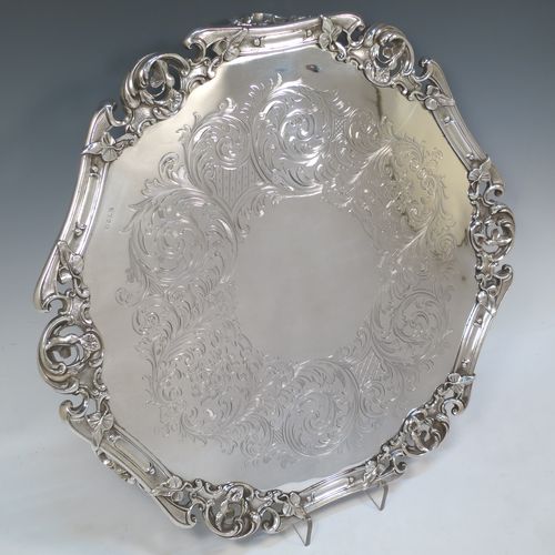 A very pretty Antique Victorian Silver Plated large salver, having an applied cast scroll border with floral decoration and piercing, with a ground having hand-engraved floral and scroll decoration surrounding a central vacant round cartouche, and all sitting on three cast scroll  feet. Made (poss.) by James Dixon And Sons of Sheffield in ca. 1860. The dimensions of this fine hand-made antique silver-plated salver are diameter 48 cms (19 inches), and height 5 cms (2 inches).  