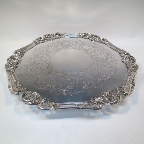A very pretty Antique Victorian Silver Plated large salver, having an applied cast scroll border with floral decoration and piercing, with a ground having hand-engraved floral and scroll decoration surrounding a central vacant round cartouche, and all sitting on three cast scroll feet. Made (poss.) by James Dixon And Sons of Sheffield in ca. 1860. The dimensions of this fine hand-made antique silver-plated salver are diameter 48 cms (19 inches), and height 5 cms (2 inches).