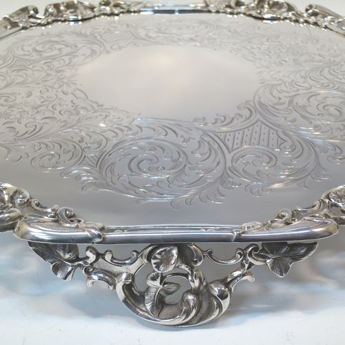 A very pretty Antique Victorian Silver Plated large salver, having an applied cast scroll border with floral decoration and piercing, with a ground having hand-engraved floral and scroll decoration surrounding a central vacant round cartouche, and all sitting on three cast scroll feet. Made (poss.) by James Dixon And Sons of Sheffield in ca. 1860. The dimensions of this fine hand-made antique silver-plated salver are diameter 48 cms (19 inches), and height 5 cms (2 inches).