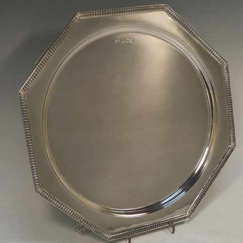 A very handsome and striking Art Deco Sterling Silver salver, having an octagonal body with an applied straight gadroon border, with a plain burnished and recessed ground, and sitting on four cast flange feet. Made by Walker and Hall of Sheffield in 1944. The dimensions of this fine hand-made Art Deco style silver salver are 32 cms (12.5 inches) diameter, and it weighs approx. 930g (30 troy ounces).  