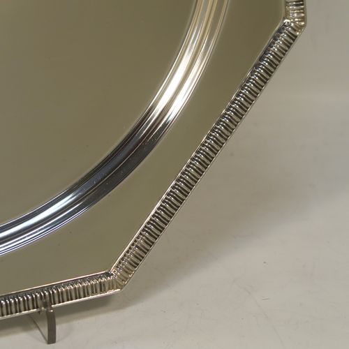 A very handsome and striking Art Deco Sterling Silver salver, having an octagonal body with an applied straight gadroon border, with a plain burnished and recessed ground, and sitting on four cast flange feet. Made by Walker and Hall of Sheffield in 1944. The dimensions of this fine hand-made Art Deco style silver salver are 32 cms (12.5 inches) diameter, and it weighs approx. 930g (30 troy ounces).