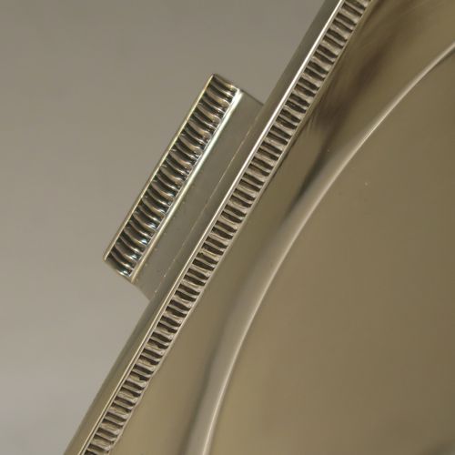A very handsome and striking Art Deco Sterling Silver salver, having an octagonal body with an applied straight gadroon border, with a plain burnished and recessed ground, and sitting on four cast flange feet. Made by Walker and Hall of Sheffield in 1944. The dimensions of this fine hand-made Art Deco style silver salver are 32 cms (12.5 inches) diameter, and it weighs approx. 930g (30 troy ounces).