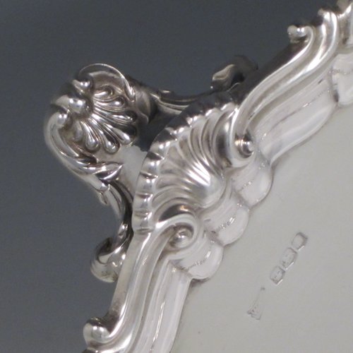 A Sterling silver salver, having a round body, with a plain burnished ground, an applied Shell & Scroll border, and sitting on three shell feet. Made by Walker and Hall of Sheffield in 1919. The dimensions of this fine hand-made silver salver are diameter 31 cms (12 inches), and it weighs approx. 658g (21 troy ounces).