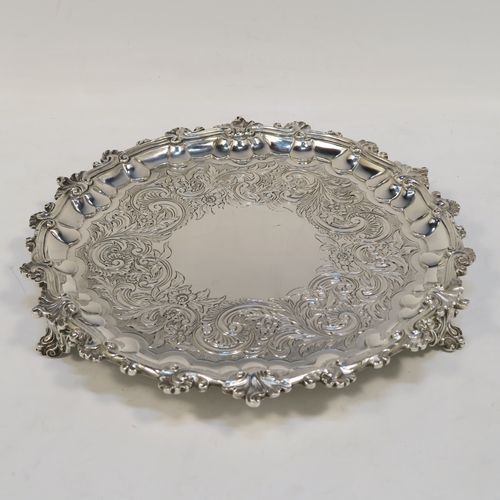 A beautiful Antique Georgian (William IV) Sterling Silver salver, having a hand-chased ground with floral and scroll decoration, an applied cast shell and scroll border and sitting on three cast foliate  feet. This pretty antique silver salver was made by the Barnard Brothers of London in 1835. The dimensions of this fine hand-made silver salver are diameter 24 cms (9.5 inches), and it weighs approx. 478g (15.4 troy ounces).  