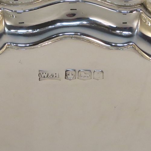 A handsome Antique Sterling Silver round salver, having a plain burnished ground, an applied Chippendale border, and sitting on three cast scroll feet. This elegant silver salver was made by Walker and Hall of Sheffield in 1924. The dimensions of this fine hand-made antique silver salver are diameter 20 cms (8 inches), and it weighs approx. 319g (10.3 troy ounces).