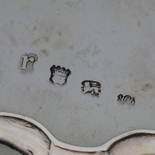 An Antique Georgian Sterling Silver salver, having a plain burnished ground, an applied shell and scroll border, and sitting on three cast hoof feet. Made by James Wilks of London in 1752. The dimensions of this fine hand-made antique silver salver are diameter 19 cms (7.55 inches), and it weighs approx. 262g (8.5 troy ounces).