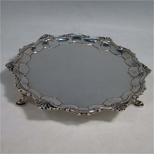 An Antique Georgian Sterling Silver salver, having a plain burnished ground, an applied shell and scroll border, and sitting on three cast hoof feet. Made by James Wilks of London in 1752. The dimensions of this fine hand-made antique silver salver are diameter 19 cms (7.55 inches), and it weighs approx. 262g (8.5 troy ounces).