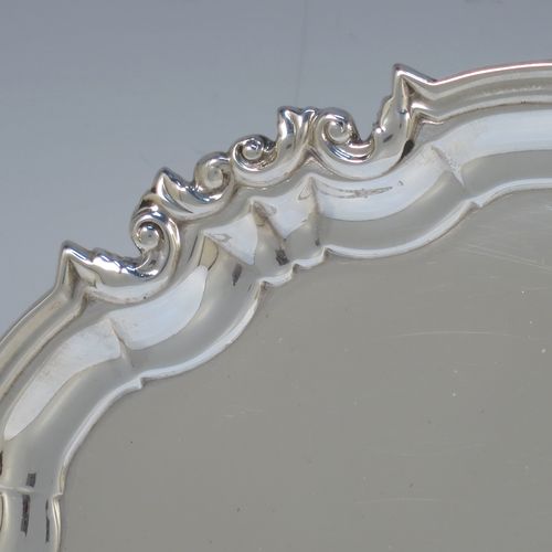 A handsome Antique Sterling Silver round salver, having a plain burnished ground, an applied scroll and floral border, and sitting on three cast scroll feet. Made by William Hutton of Sheffield in 1917. The dimensions of this fine hand-made antique silver salver are diameter 20 cms (8 inches), and it weighs approx. 340g (11 troy ounces).