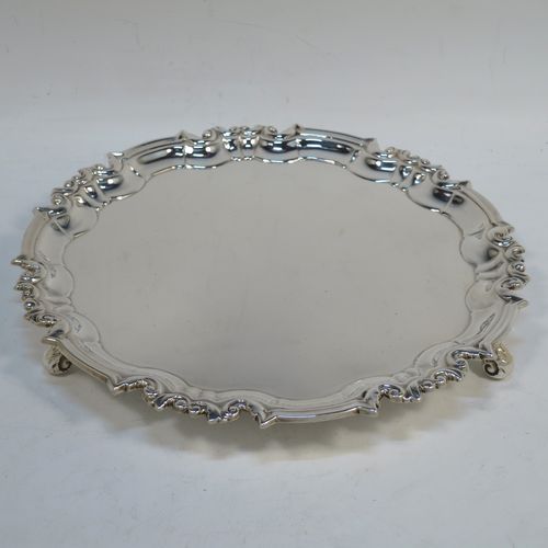 A handsome Antique Sterling Silver round salver, having a plain burnished ground, an applied scroll and floral border, and sitting on three cast scroll feet. Made by William Hutton of Sheffield in 1917. The dimensions of this fine hand-made antique silver salver are diameter 20 cms (8 inches), and it weighs approx. 340g (11 troy ounces).
