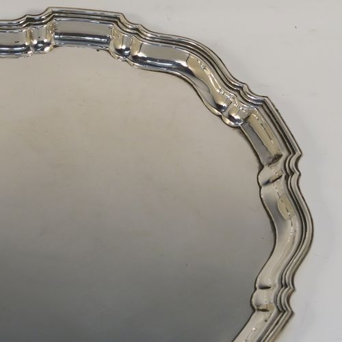 An elegant Sterling Silver round salver, having a plain burnished ground, an applied Chippendale border, and sitting on three cast scroll feet. This handsome silver salver was made by the Barker Brothers of Birmingham in 1923. The dimensions of this fine hand-made silver salver are diameter 20 cms (8 inches), and it weighs approx. 350g (11.3 troy ounces).