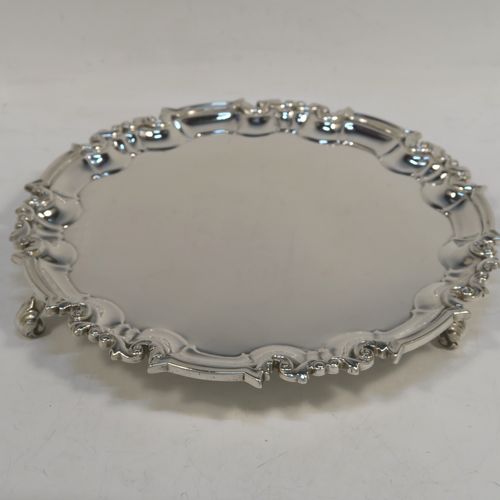 A very handsome Antique Victorian Sterling Silver round salver, having a plain burnished ground, an applied scroll border and sitting on three cast scroll feet. This beautiful antique silver salver was made by Edward Hutton of London in 1886. The dimensions of this fine hand-made antique silver salver are diameter 20 cms (8 inches), and it weighs approx. 422g (13.6 troy ounces).  