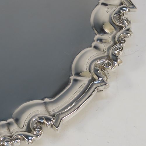 A very handsome Antique Victorian Sterling Silver round salver, having a plain burnished ground, an applied scroll border and sitting on three cast scroll feet. This beautiful antique silver salver was made by Edward Hutton of London in 1886. The dimensions of this fine hand-made antique silver salver are diameter 20 cms (8 inches), and it weighs approx. 422g (13.6 troy ounces).